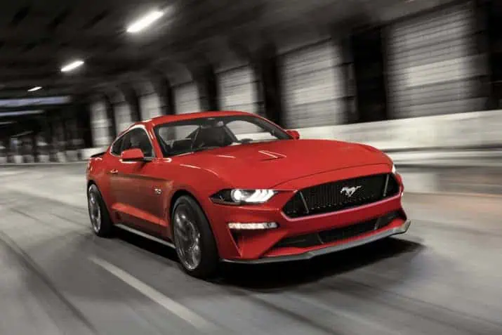 Red sports car driving through a tunnel, showcasing sleek design and speed.