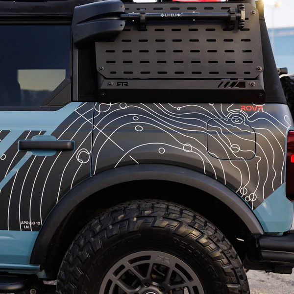 Custom blue off-road SUV with topographic design wrap and rugged tires. Adventure vehicle detailing.
