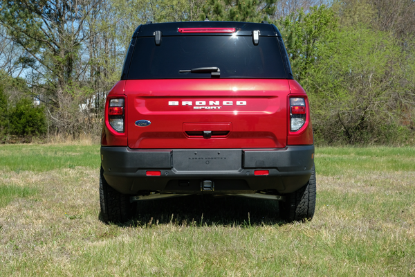 Red Ford Bronco Sport SUV parked on grass, rear view with visible logo and tail lights.